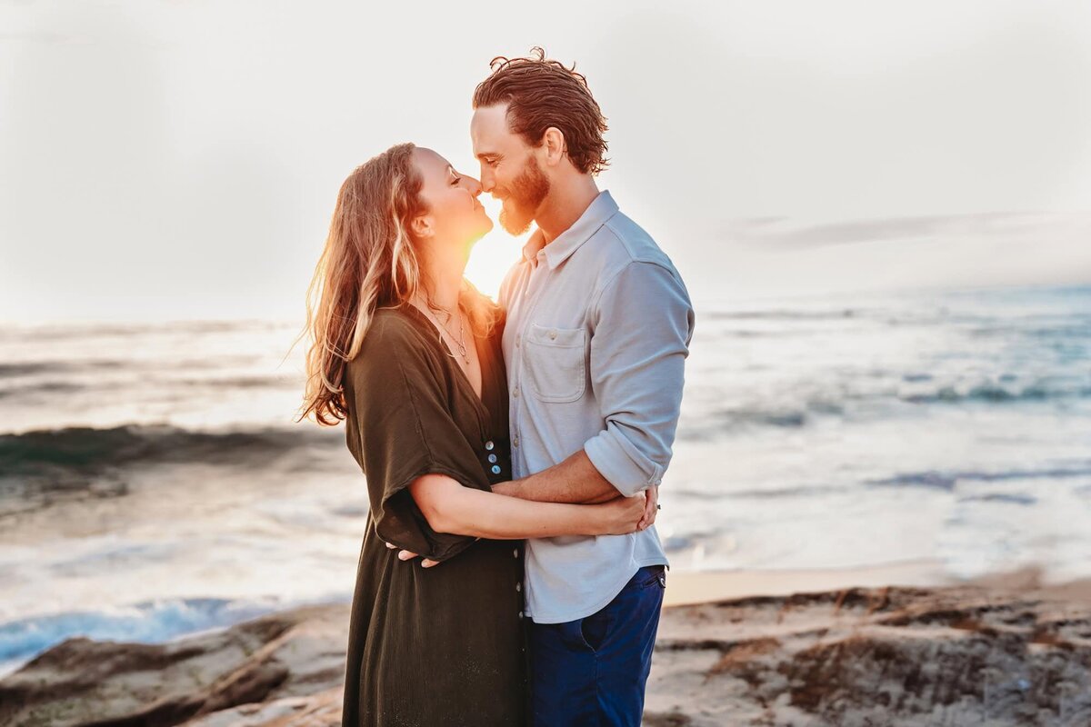 Couple embracing on Windansea beach at sunset, photographed by San Diego lifestyle family photographer.
