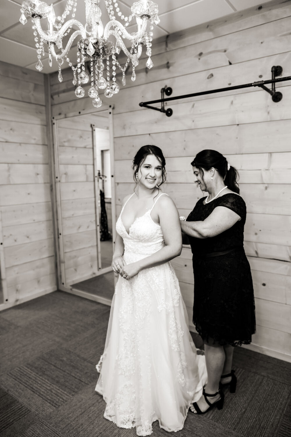 Bride getting ready with mother’s help in a rustic room