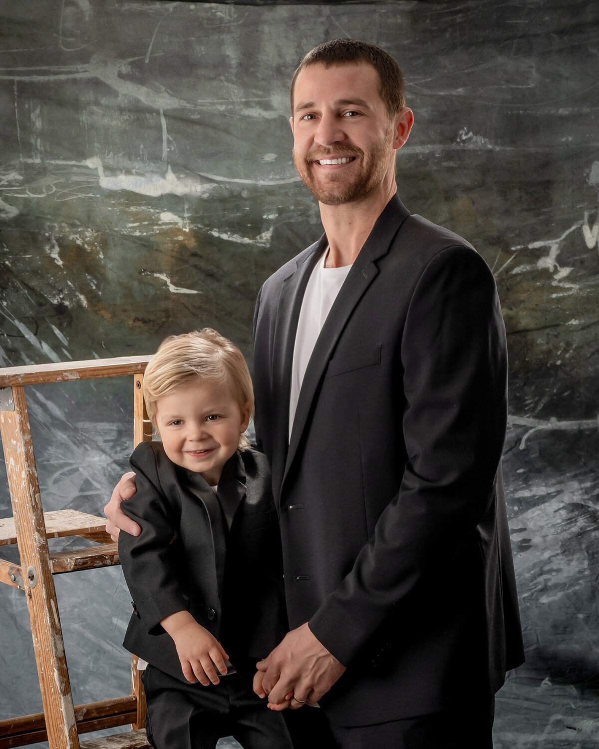 A dad and son stand next to each other and smile