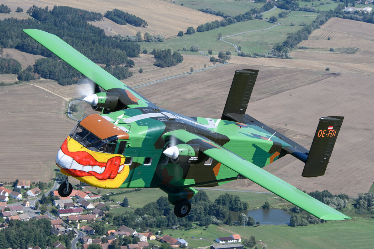 Die Pink Skyvan fliegt über die verschneiten Alpen. Zu sehen ist das Flugzeug im Flug. Die bunte und auffällige Lackierung sticht heraus