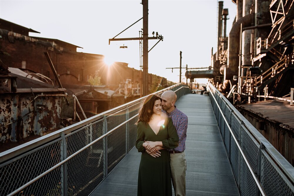 Bride and groom holding hands looking at each other while standing in front of rolling hills with the sunlight coming down on them