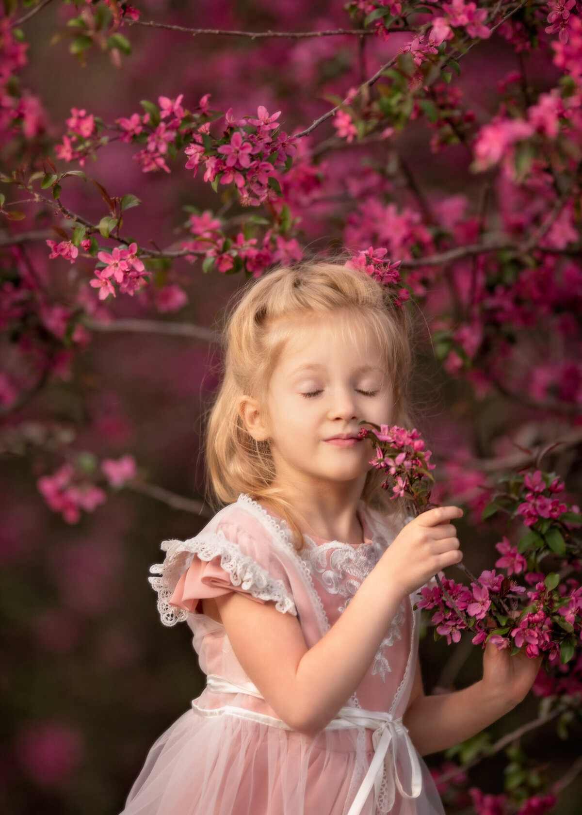 Adorable close-up portrait of a young girl enjoying a blooming tree in springtime. Captured in Overland Park, Kansas, this vibrant setup is perfect for nature-inspired child photography.