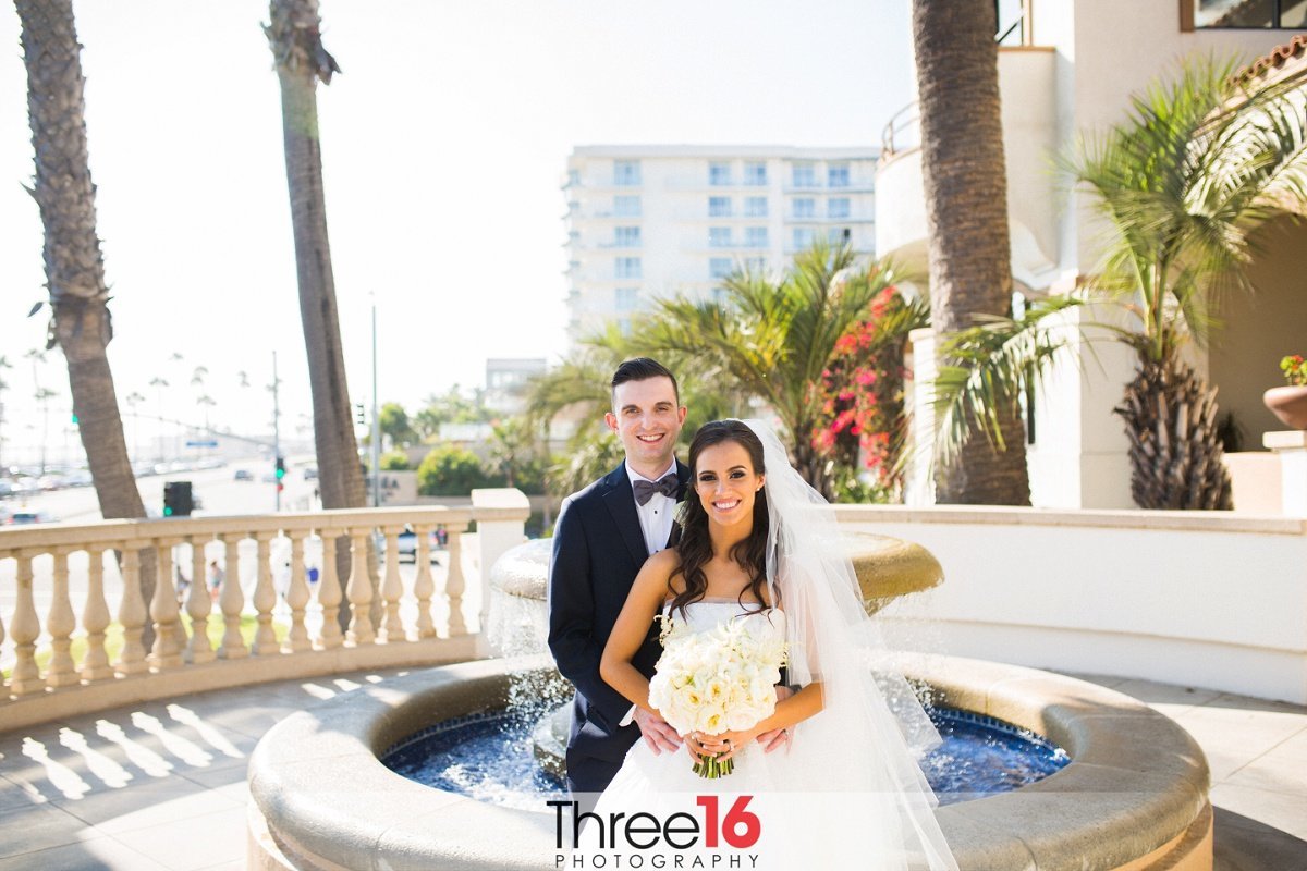 Bride and Groom pose for photo in front of water fountain