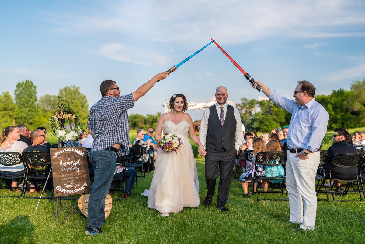 Bride and groom walk down the aisle under light sabers at Barn at Crocker's Creek in Minnesota.