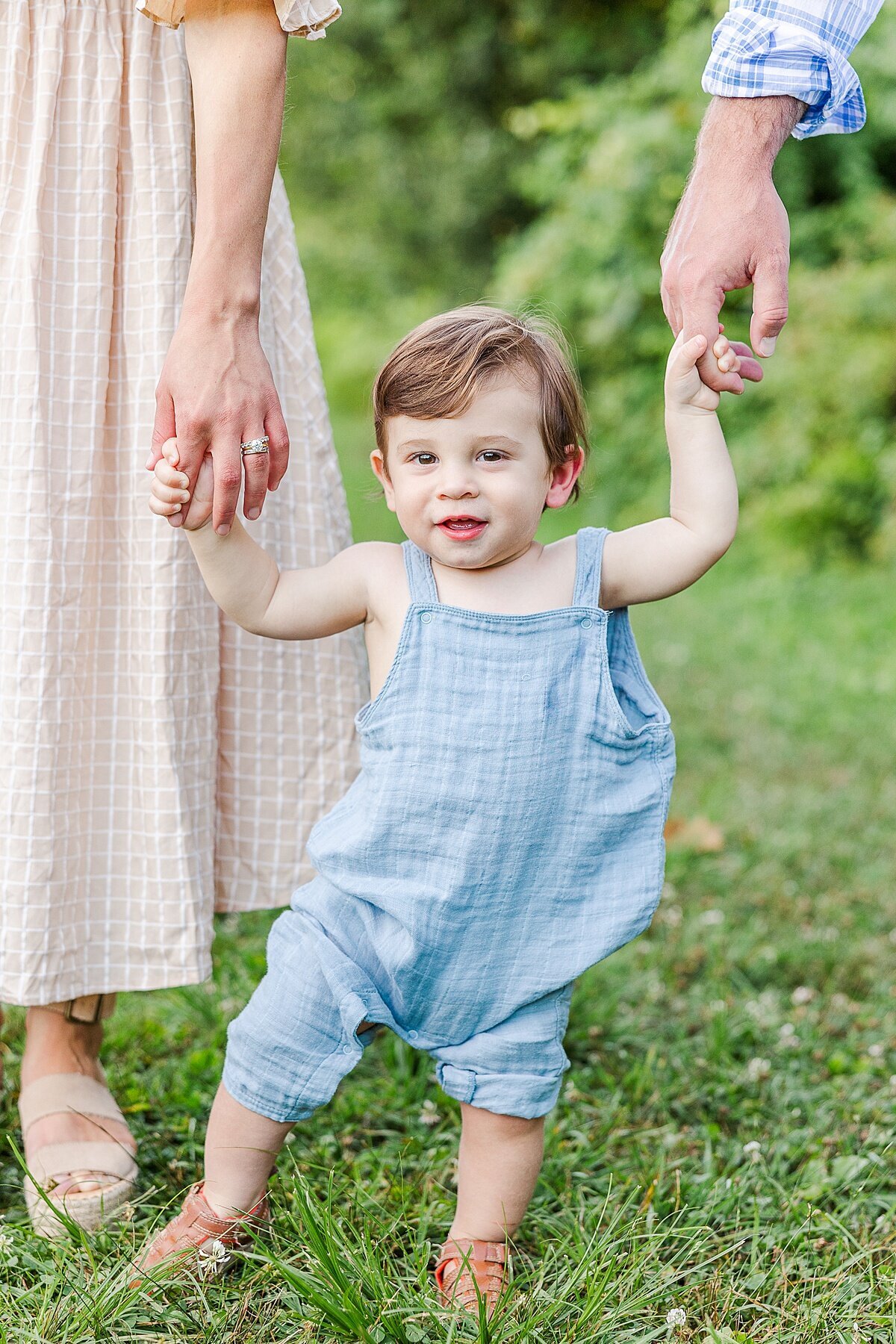 boy holds parents hands during Family photo session with Sara Sniderman Photography at Heard Farm in Wayland Massachusetts