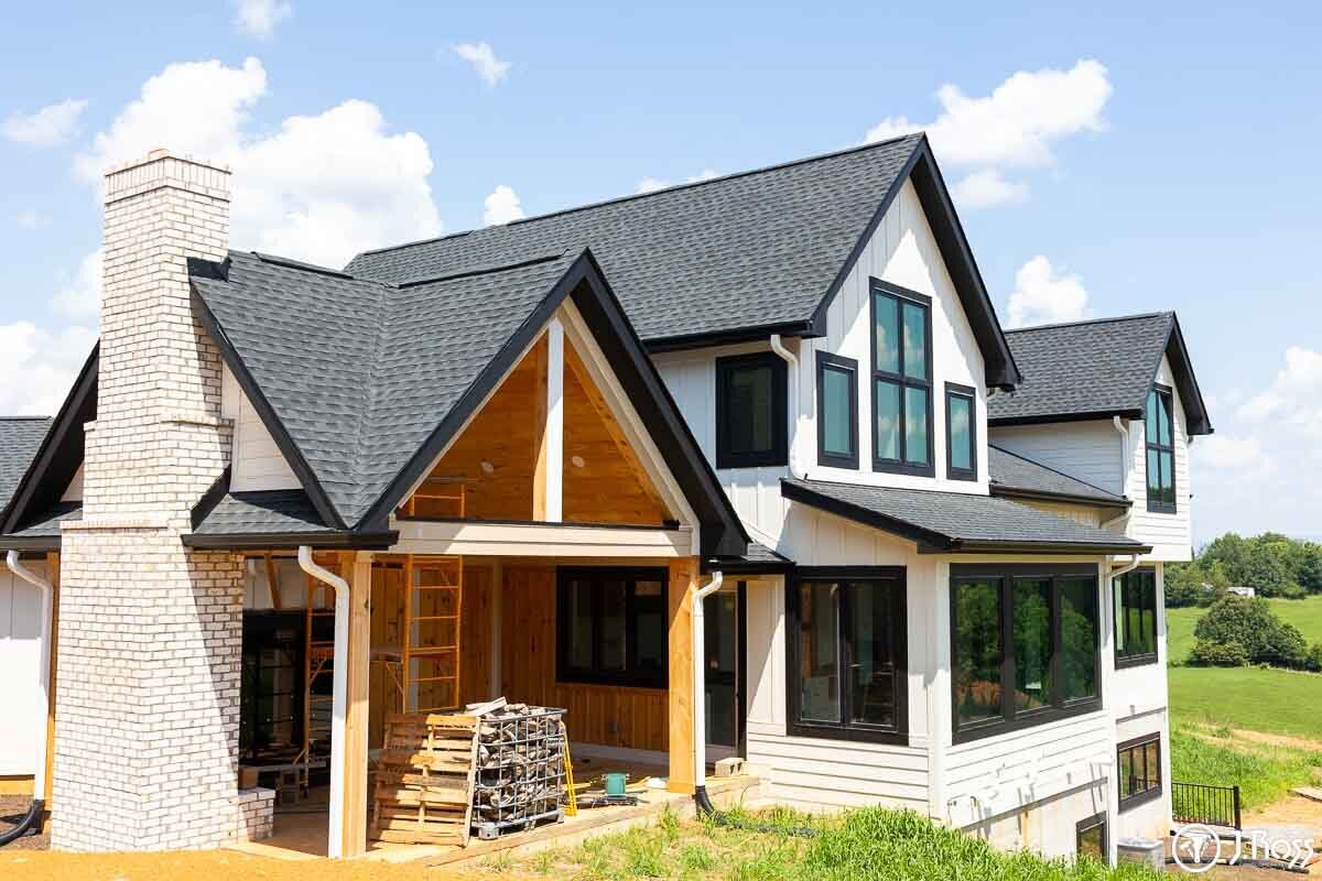 Close-up of the home's white painted siding and chimney with light brick and wood-clad porch entrance, highlighting the detailed home outside painting, Kingsport, Tennessee.