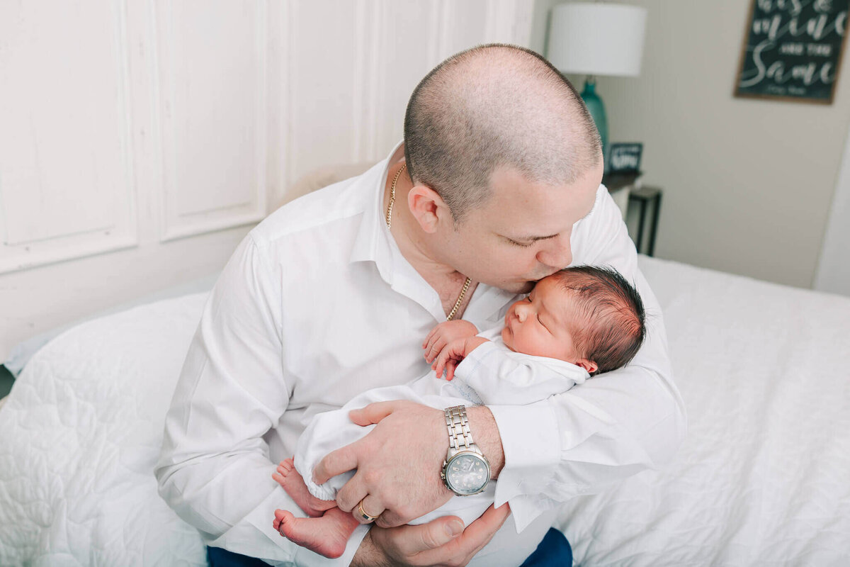 Dad kissing baby boy on top of the head during their newborn session in Aiken, South Carolina