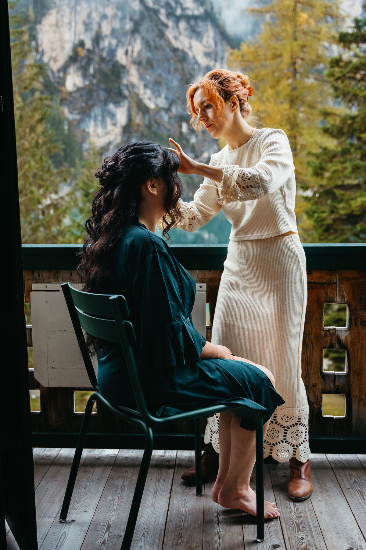 Bride getting hair styled on balcony overlooking Lago di Braies