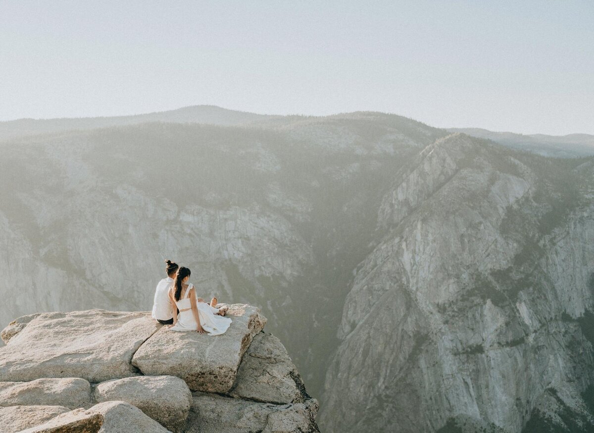 Couple sitting on a cliff admiring Yosemite