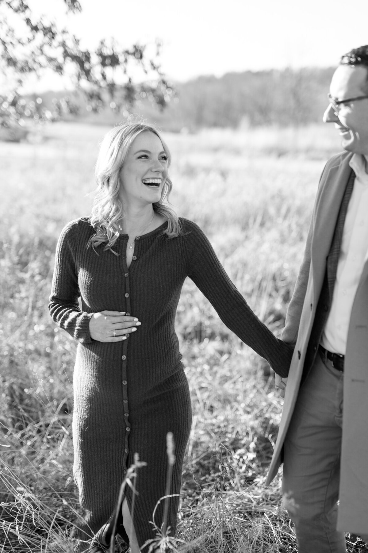 Mom and dad-to-be smiling at one another while laughing. Black and white image