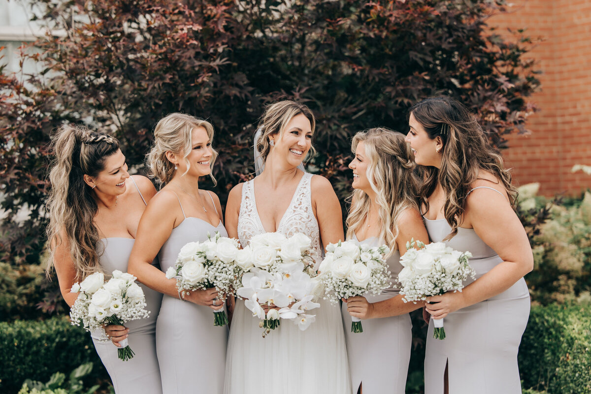 Bridesmaids holding white bouquets posing for fun photos