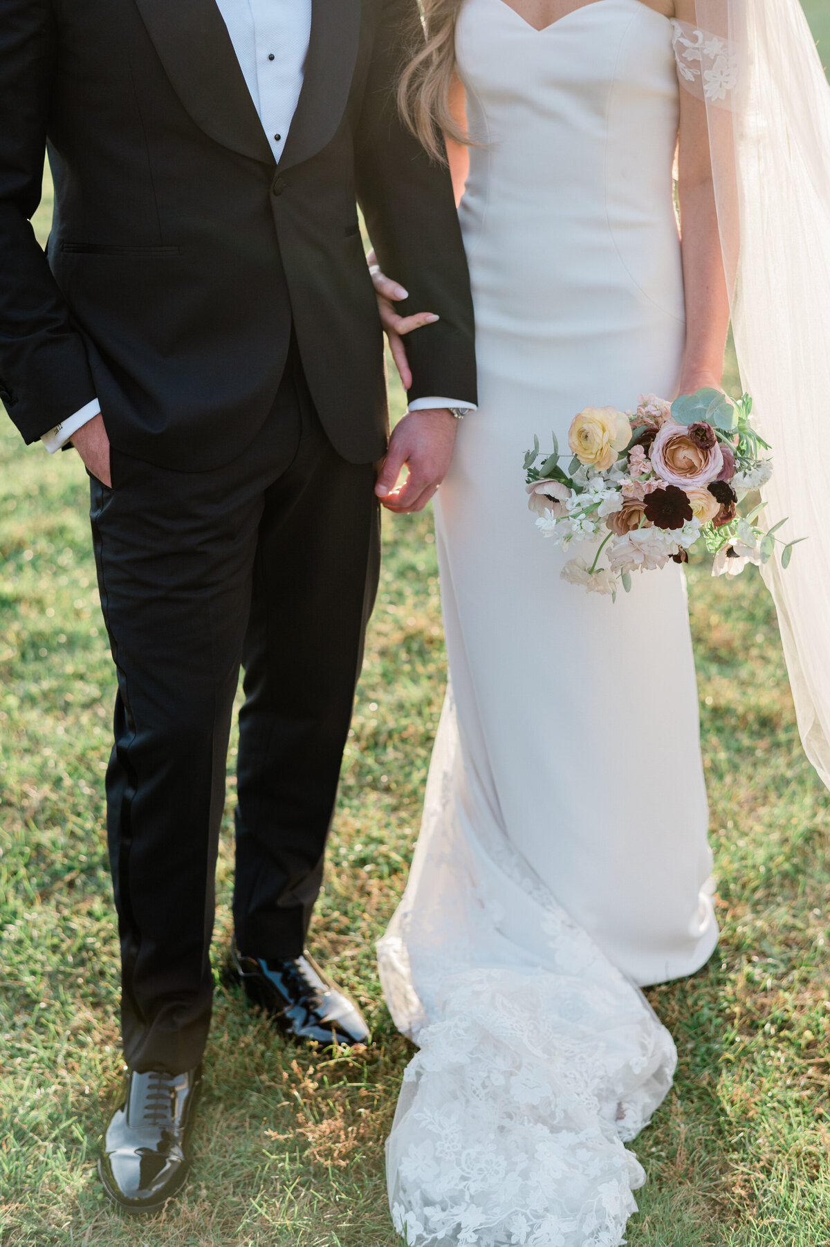Bride and groom stand in the grass 