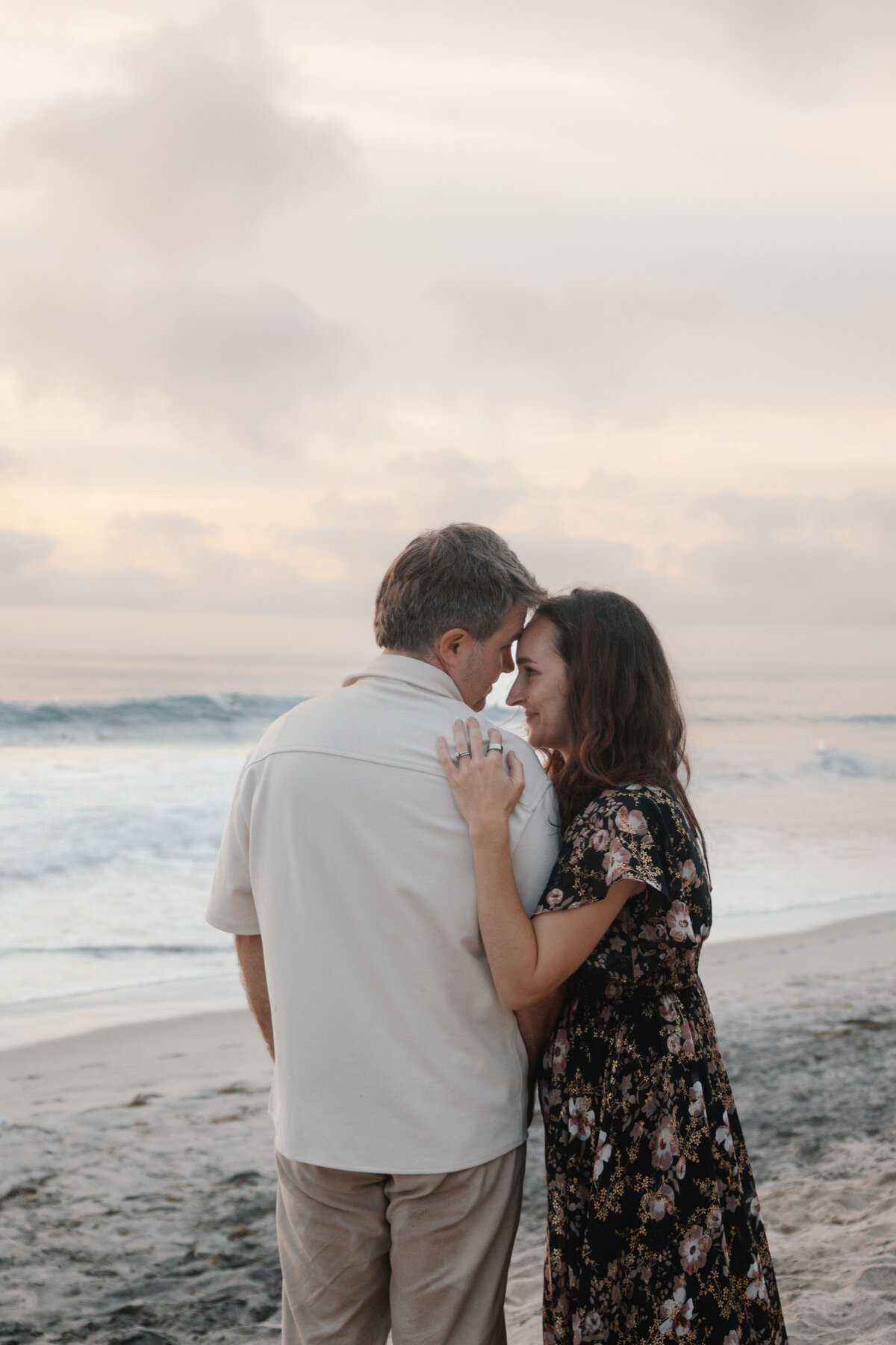 mom and dad put their foreheads together and lovingly look into each other's eyes on the beach