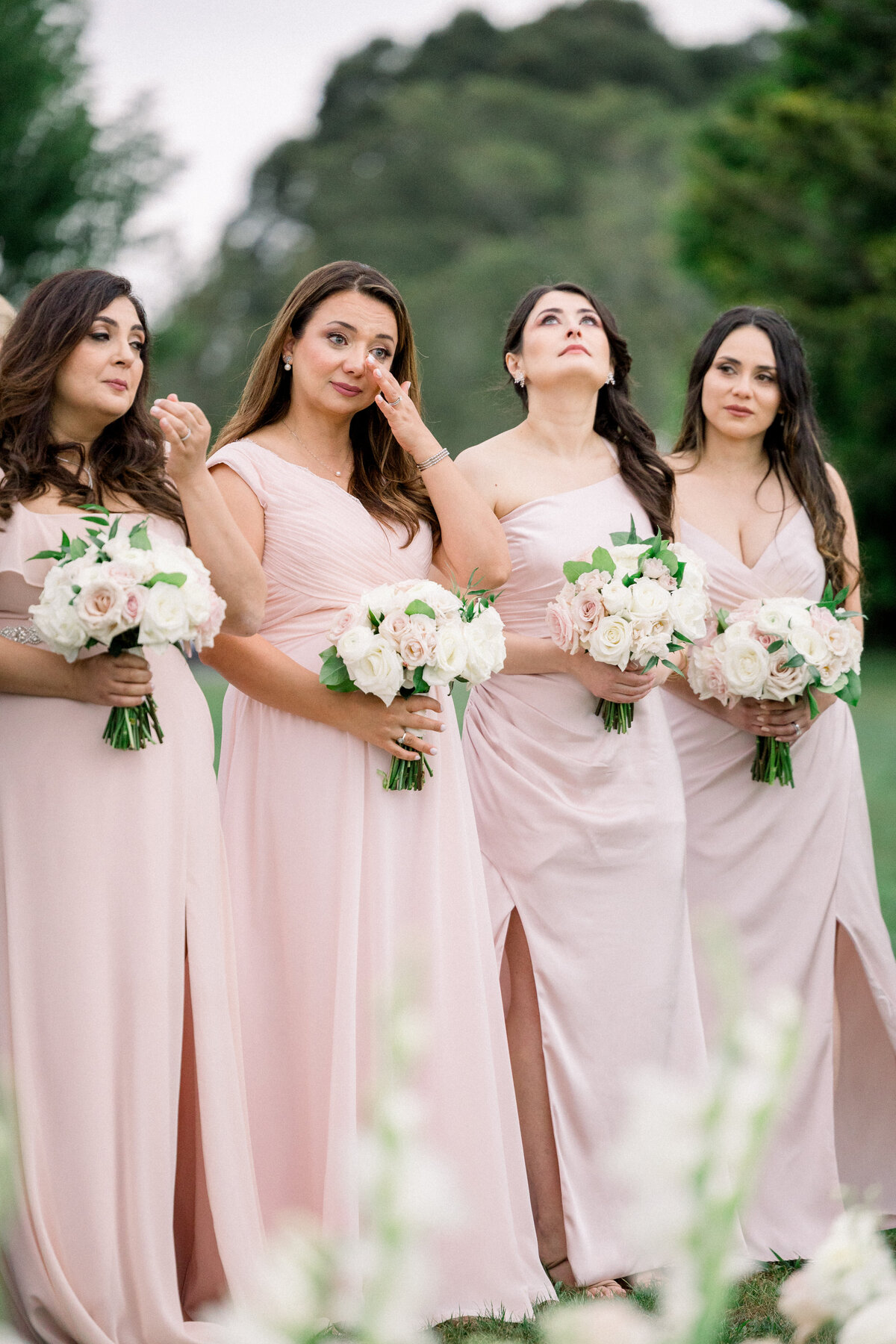 bridesmaids in blush pink gowns tear up during ceremont at rosecliff mansion