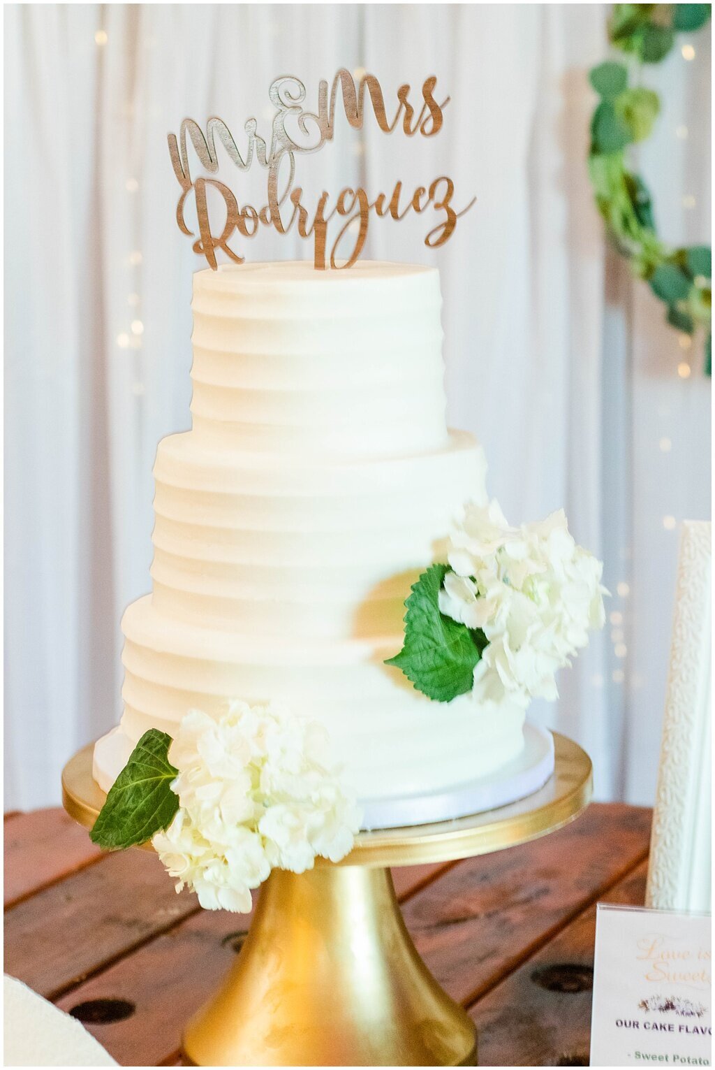 white wedding cake with greenery and rose gold details