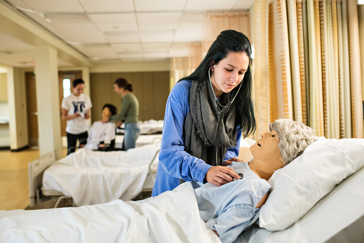 A nursing student practices on a dummy  for a college nursing program.