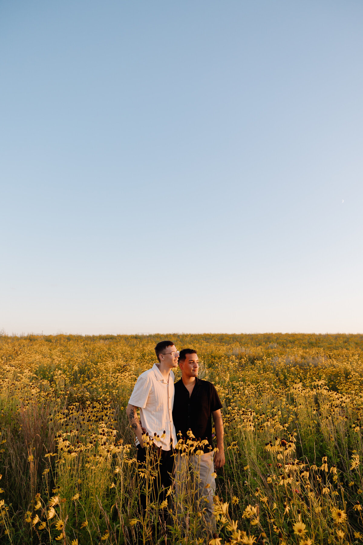A couple standing in a field of tall grass and flowers