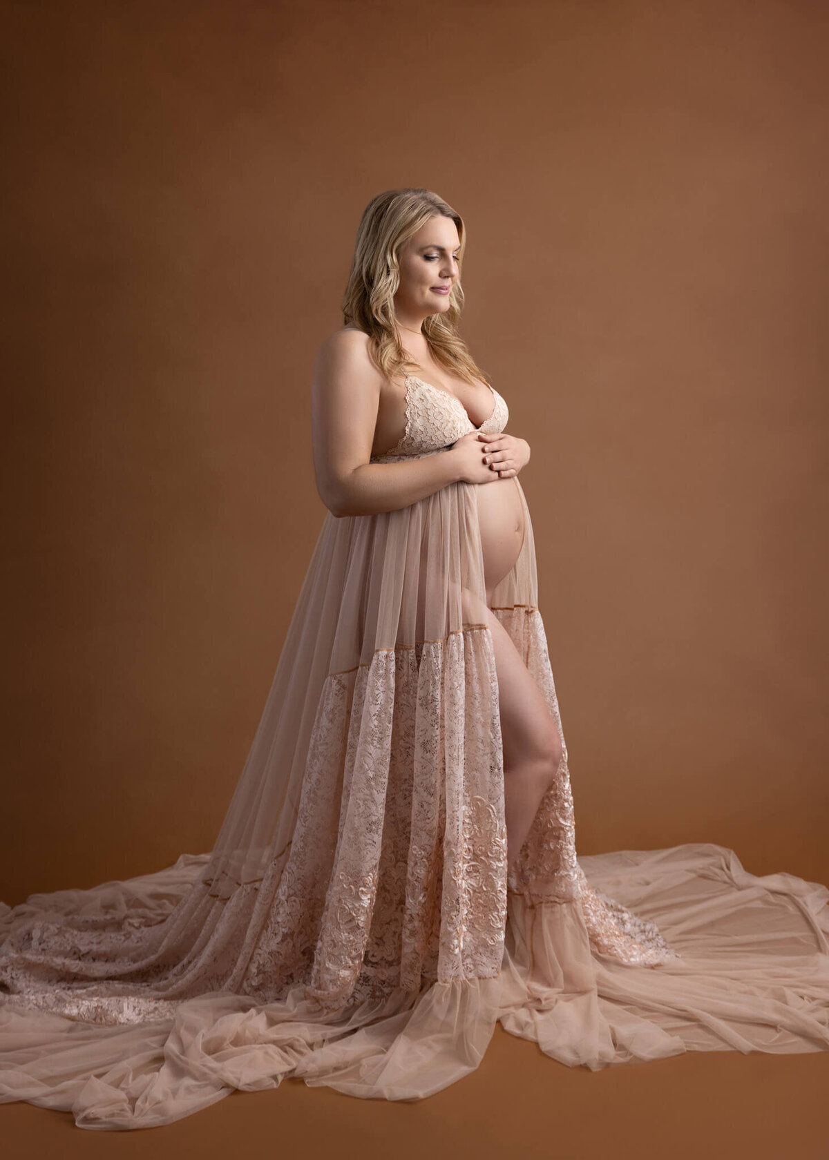 pregnant woman in flowy dress with both hands on her belly