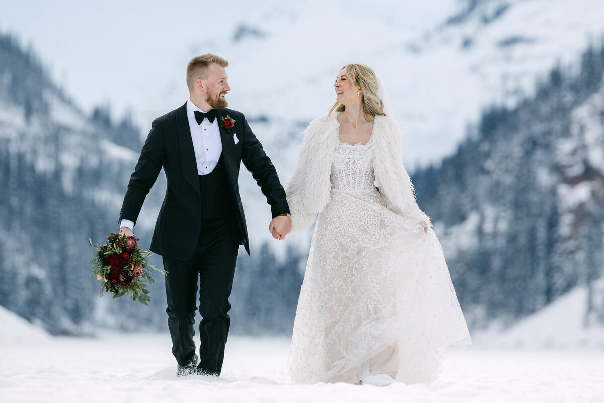 A breathtaking summer wedding at Chateau Lake Louise, where the bride and groom walk down the aisle with the majestic Victoria Glacier and Lake Louise as their backdrop. Guests rise in celebration, surrounded by the serene beauty of the turquoise lake and towering mountain peaks.