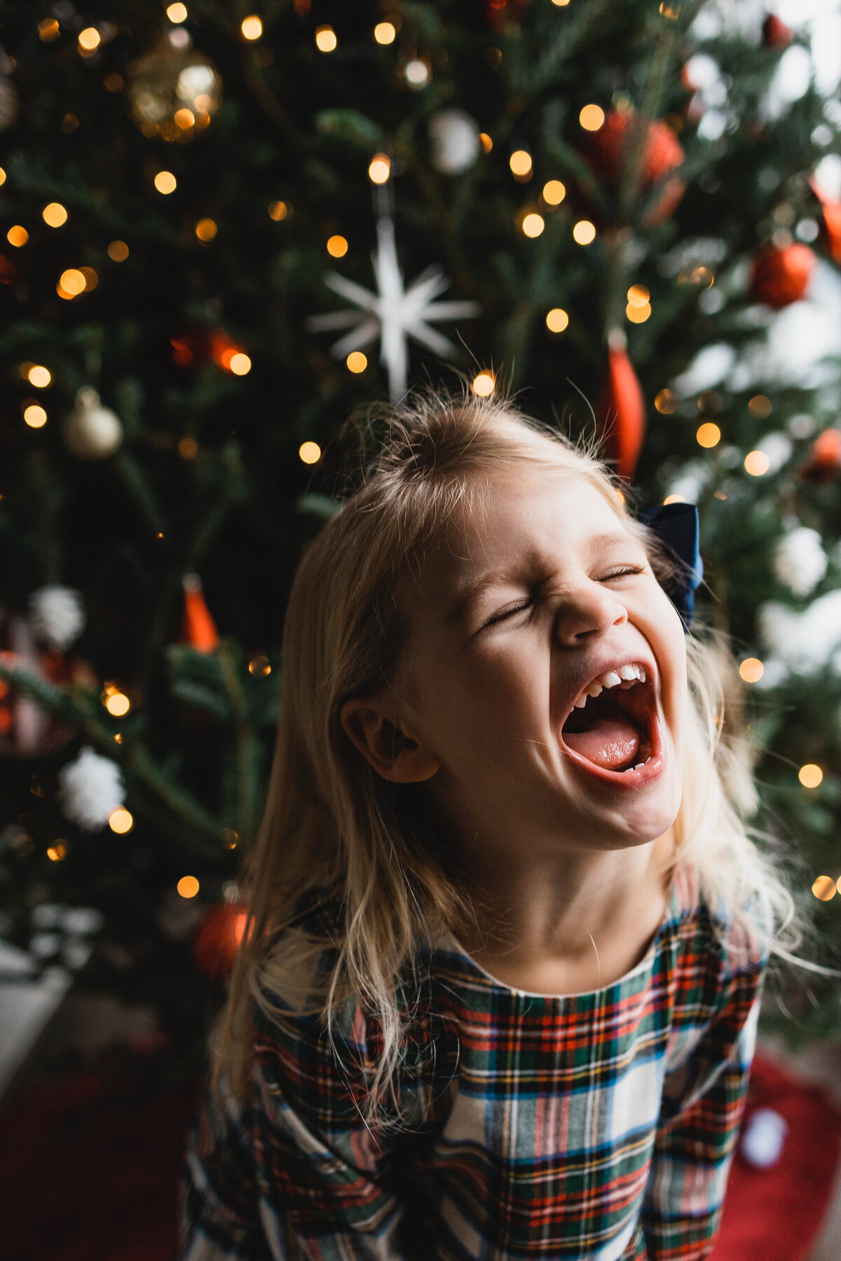 Little girl joyfully laughing in front of a Christmas tree