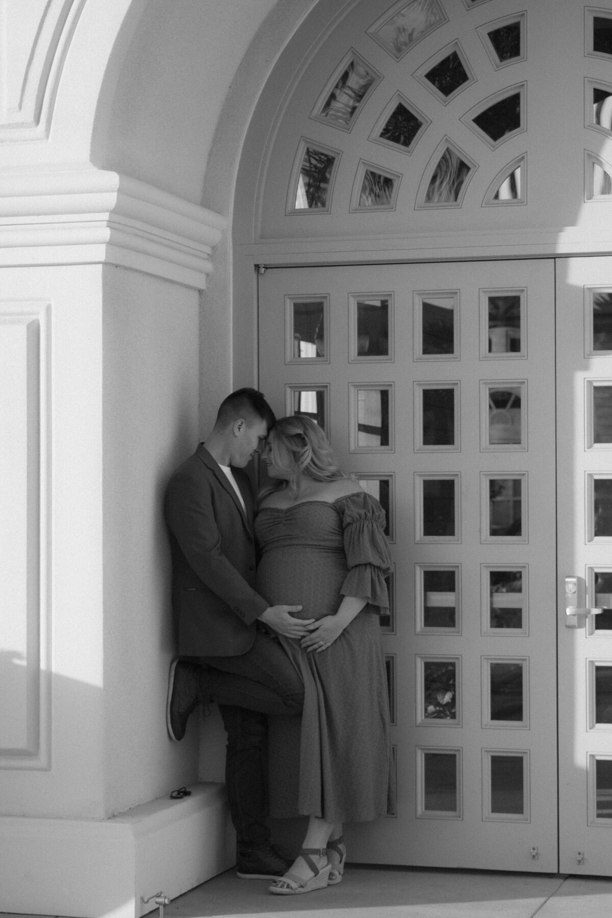 expecting mom and dad having an intimate moment in front of the botanical building in balboa park
