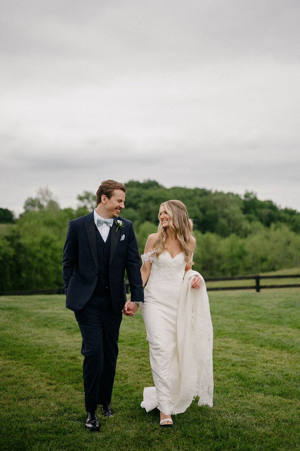 Bride and groom walking in a open field venue