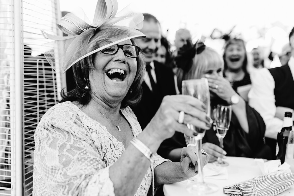 Black and white photo of woman in hat enjoying wedding