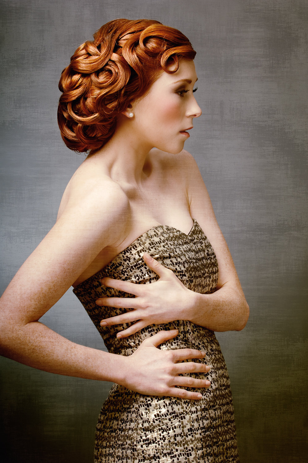 side profile of female model with red hair in vintage style wearing gold dress
