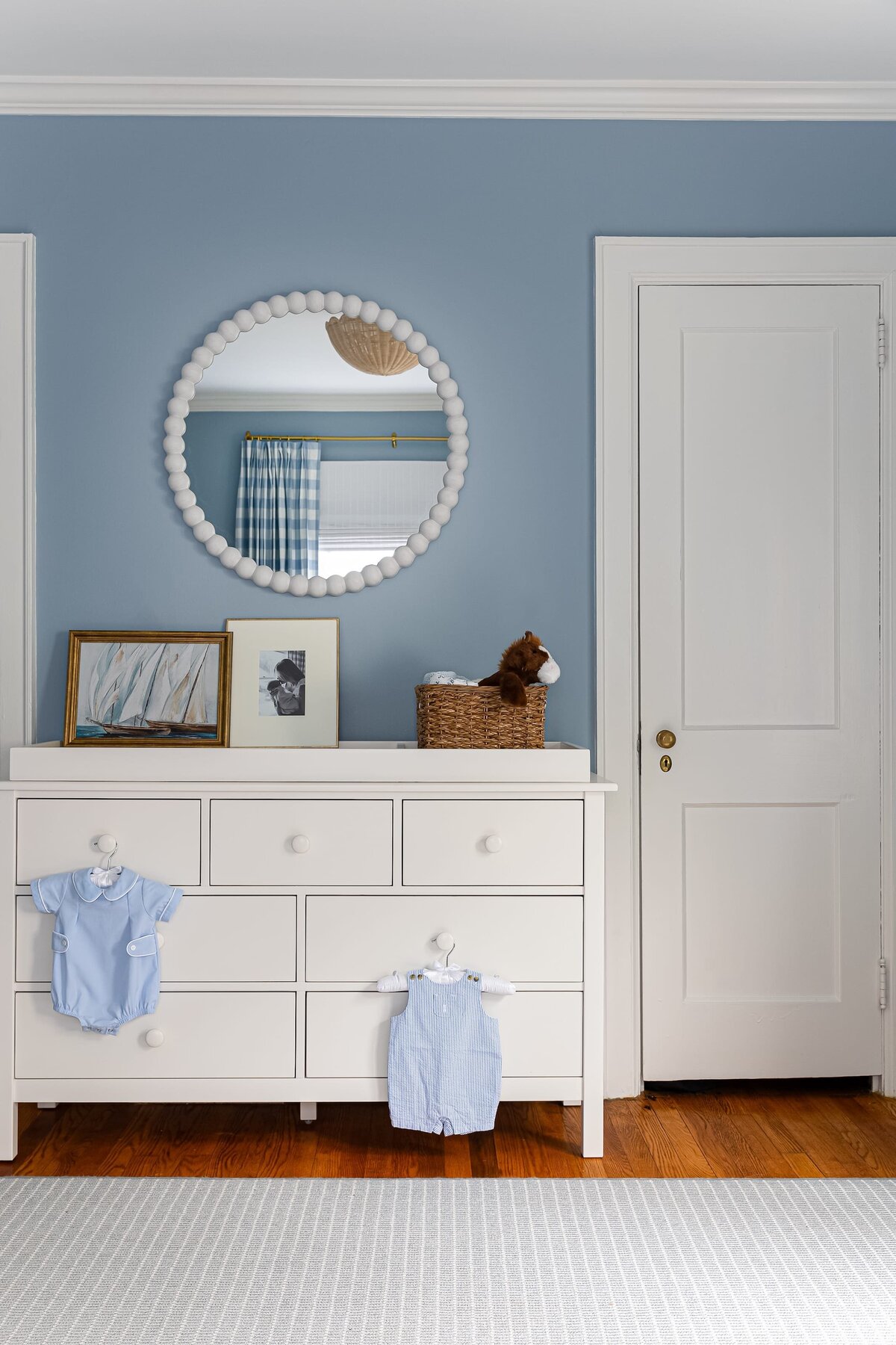 melinda chesson interiors bay street nursery with round mirror and white changing table and dark wood floors