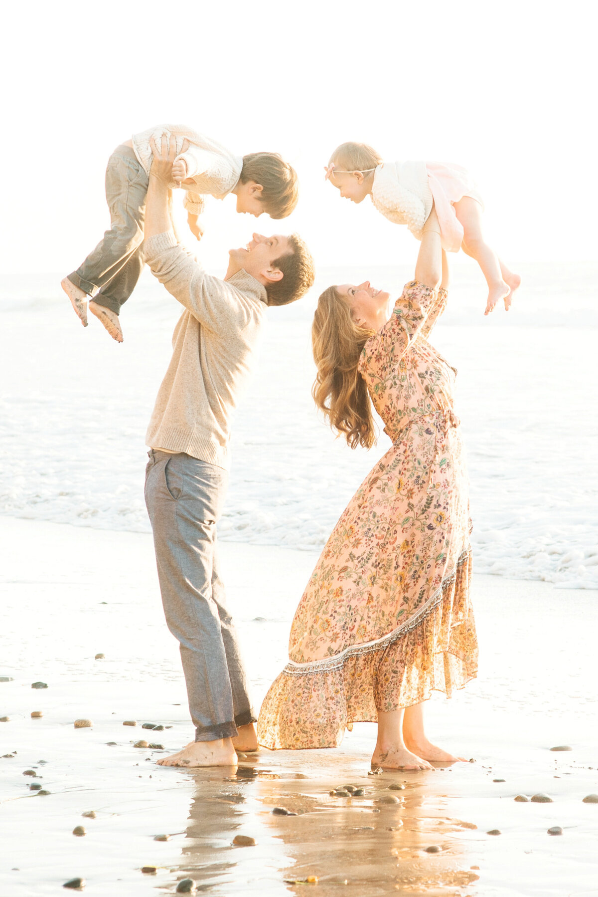 Family Photographer, mother and father lifting their two children over their heads and smiling