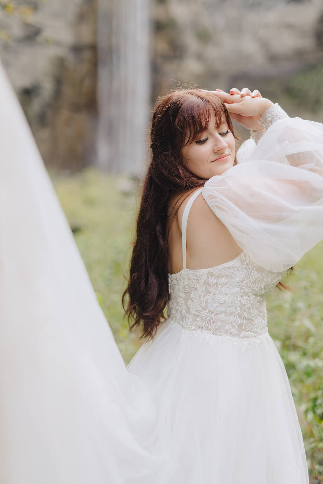 Bride with flowing dress in front of waterfall