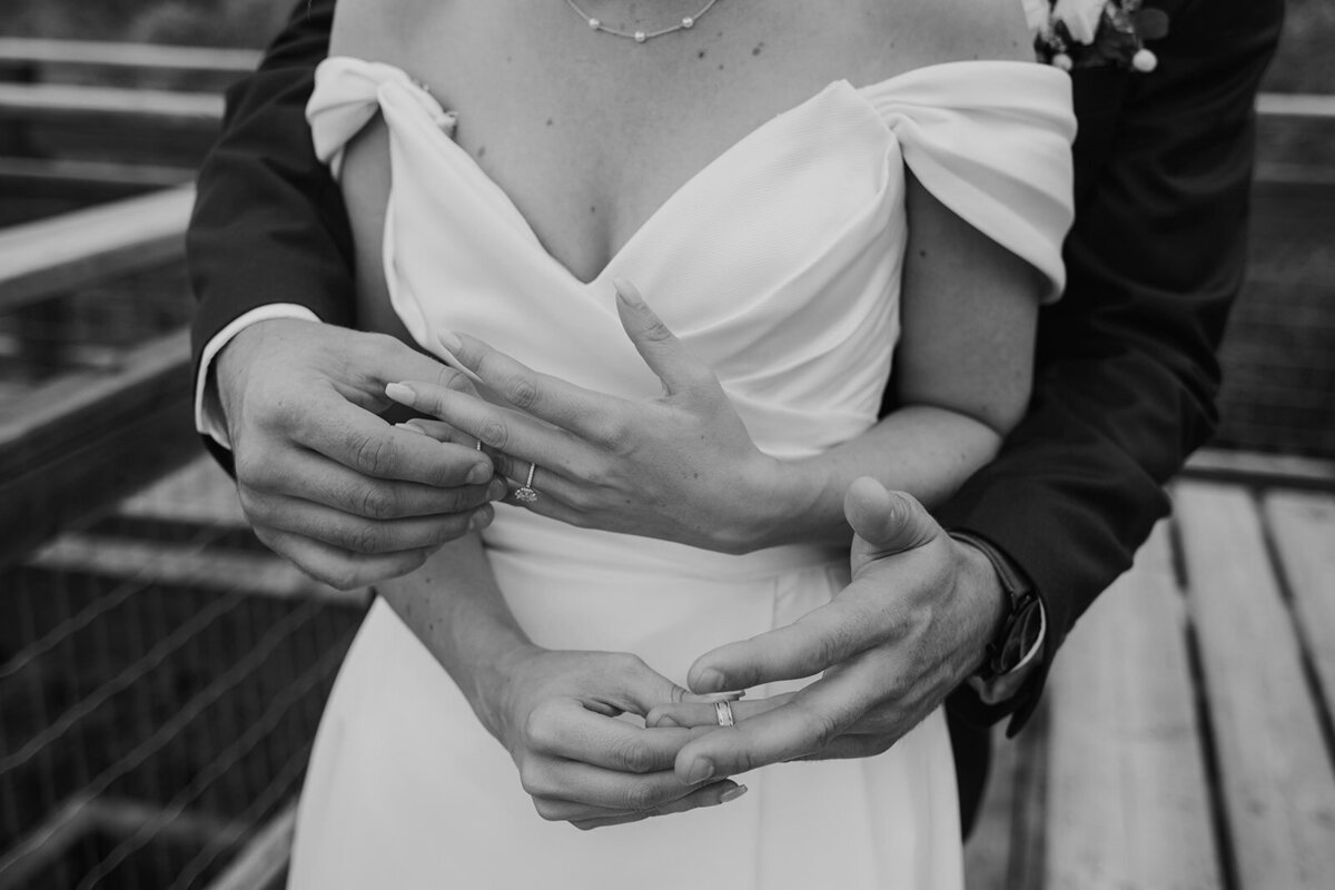 A recently wed couple embraces each other & their wedding rings