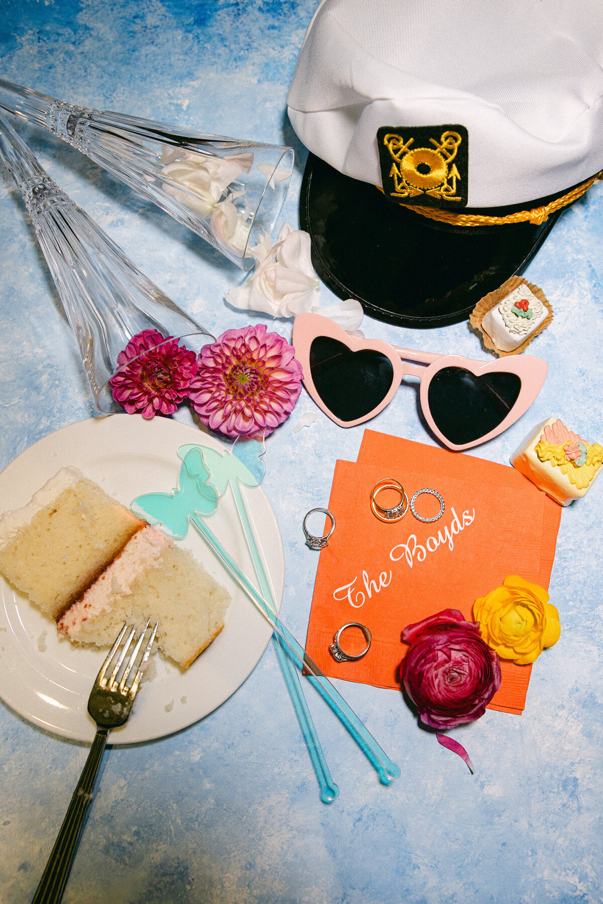 A wedding photo of a slice of cake, a sailors hat and the wedding rings