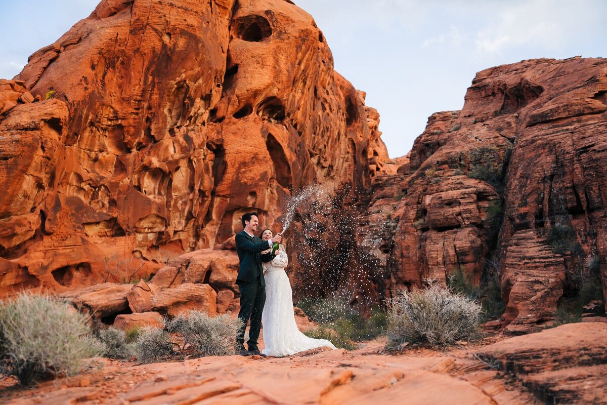 A couple popping their champagne during their elopement in Valley of fire close to Las Vegas.