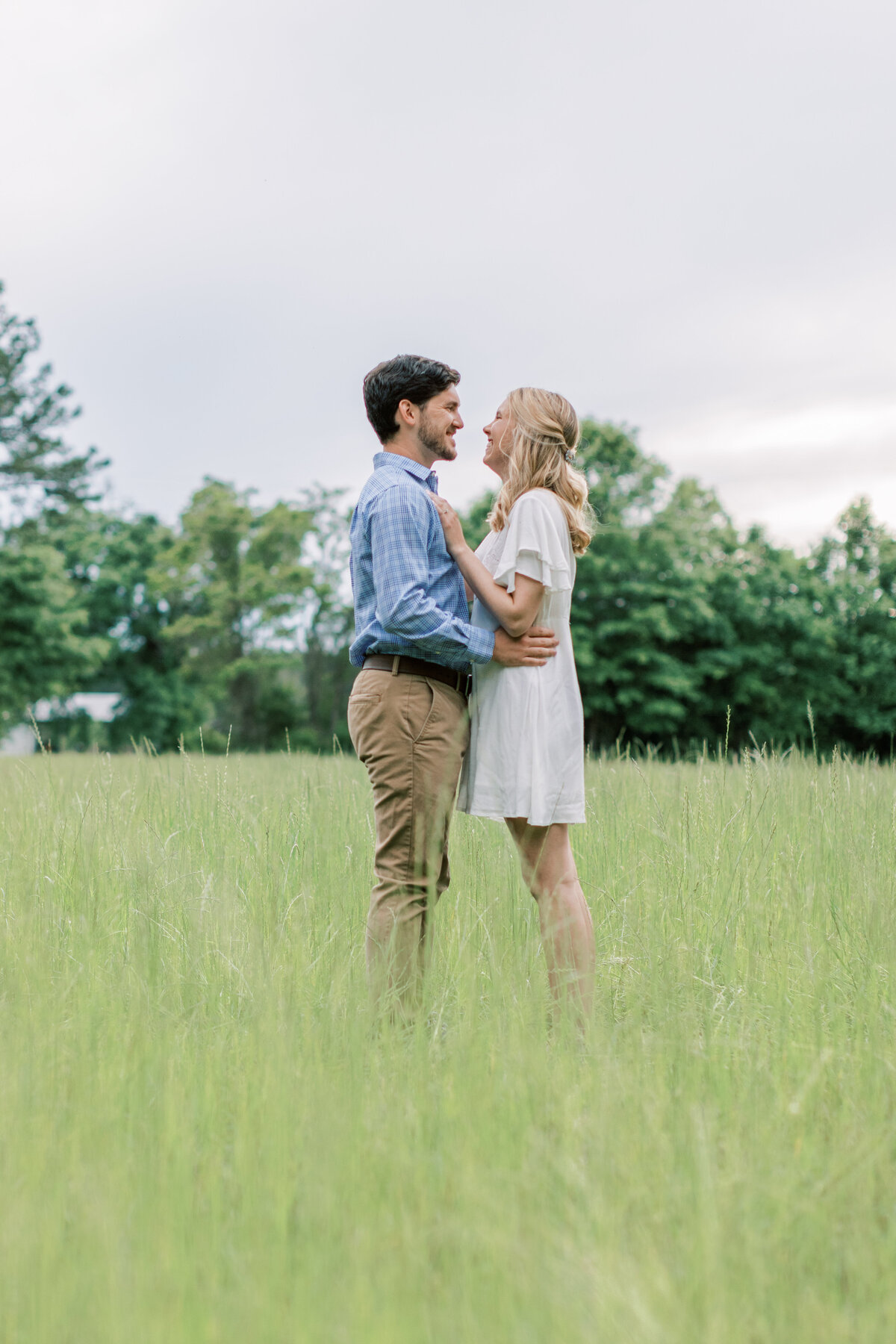 A couple faces each other for their field engagement photos.