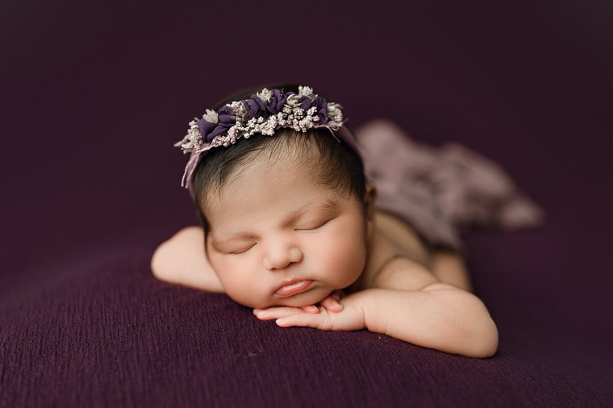 Newborn baby girl on purple backdrop by Harrisonburg newborn photographer