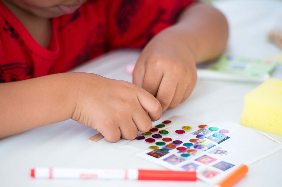 Ottawa event photos of a little boy's hands choosing stickers at a craft table at a corporate children's event.  Captured by JEMMAN Photography COMMERCIAL
