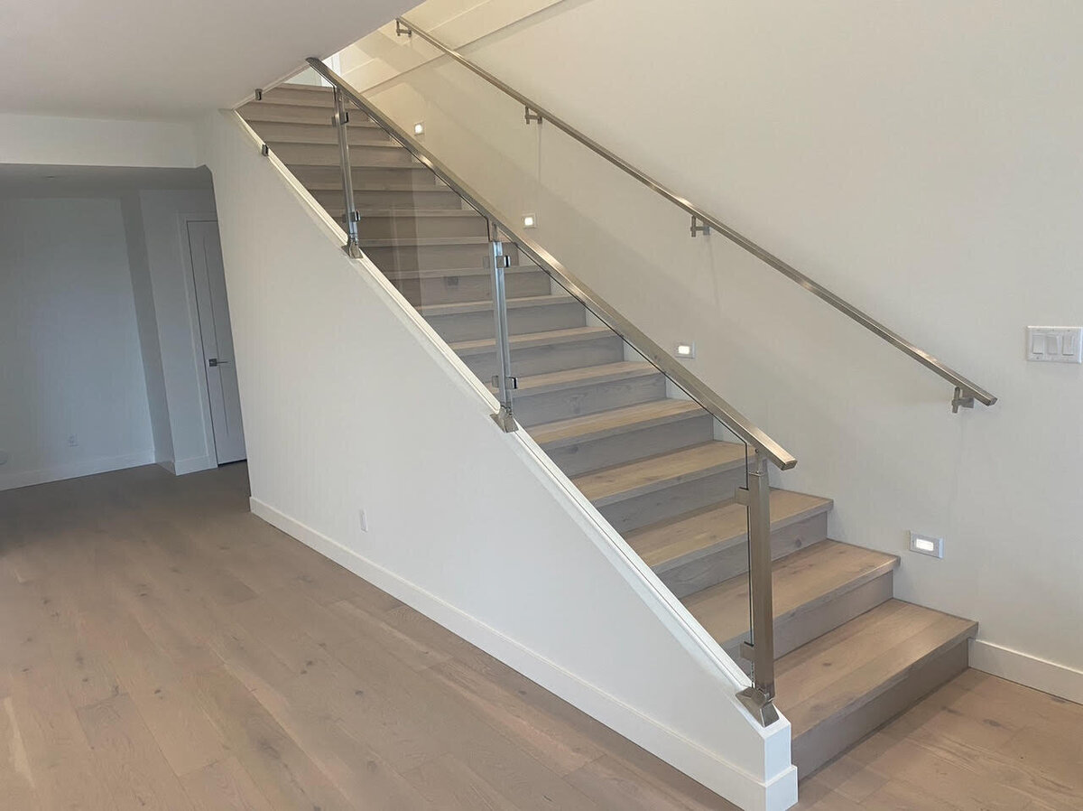 Contemporary interior stairwell design with hardwood floors and steel railings.