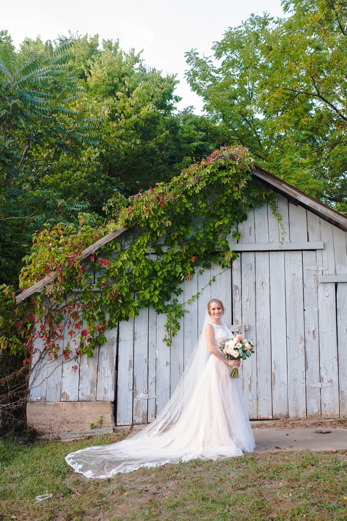 Full length photograph of a beautiful bride in front of a barn at Chandler Hill Vineyard.