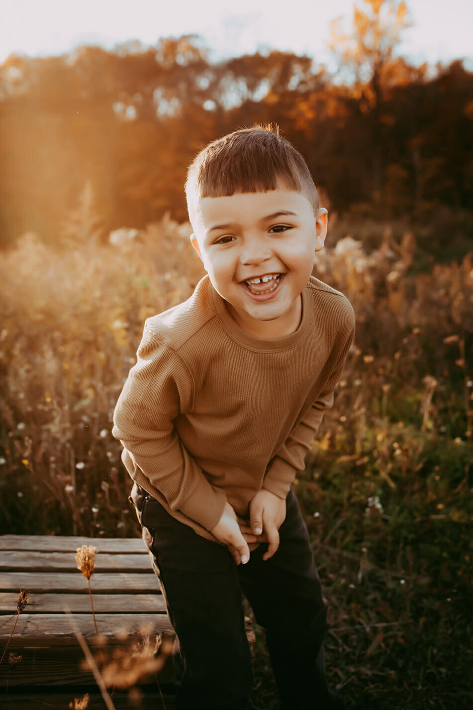a little boy standing and leaning over laughing at the camera