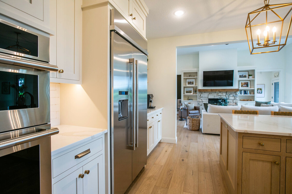 Open kitchen with white cabinets, large island, and quartz countertops in an Otsego custom home