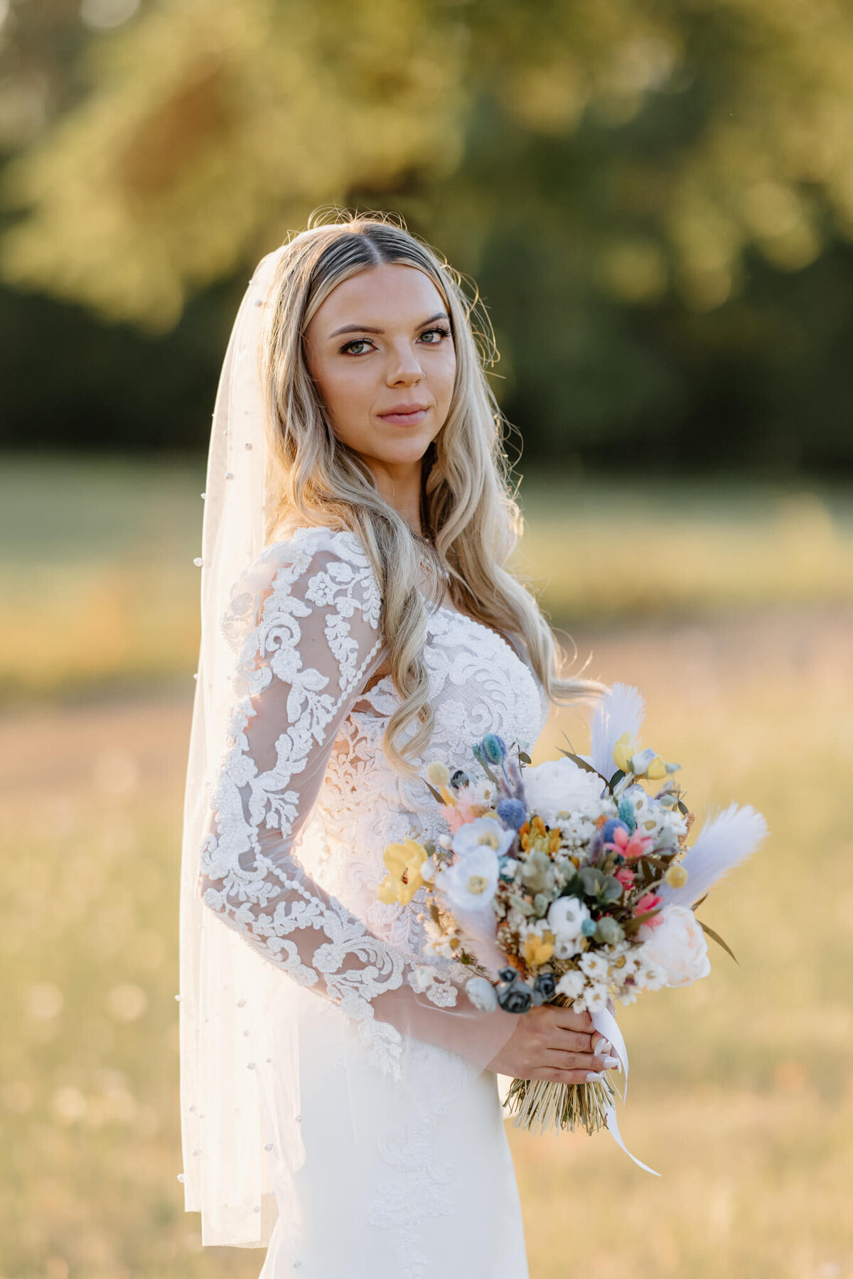 bride in white lace gown and pearl beaded  white veil holding bridal bouquet during bridal portraits after wedding ceremony