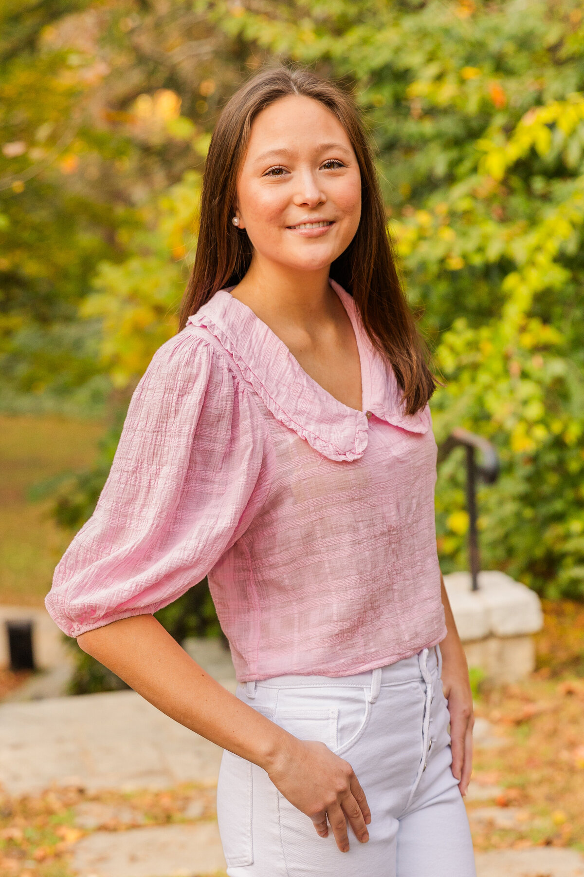 teenager wearing a white jeans and a pink blouse looking at the camera hands in pockets during lifestyle photoshoot