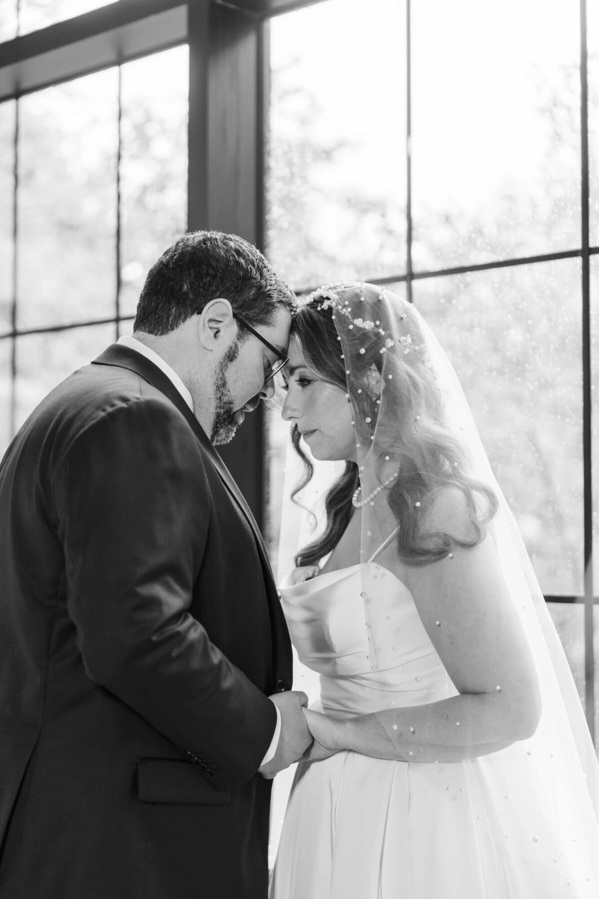 Bride with veil and groom pose inside the Roundhouse Hotel wedding ceremony space during a rainstorm