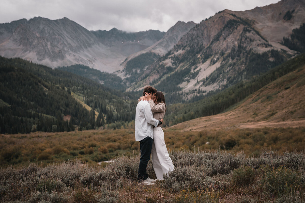 Couple enjoying a winter engagement session in a snowy Aspen grove