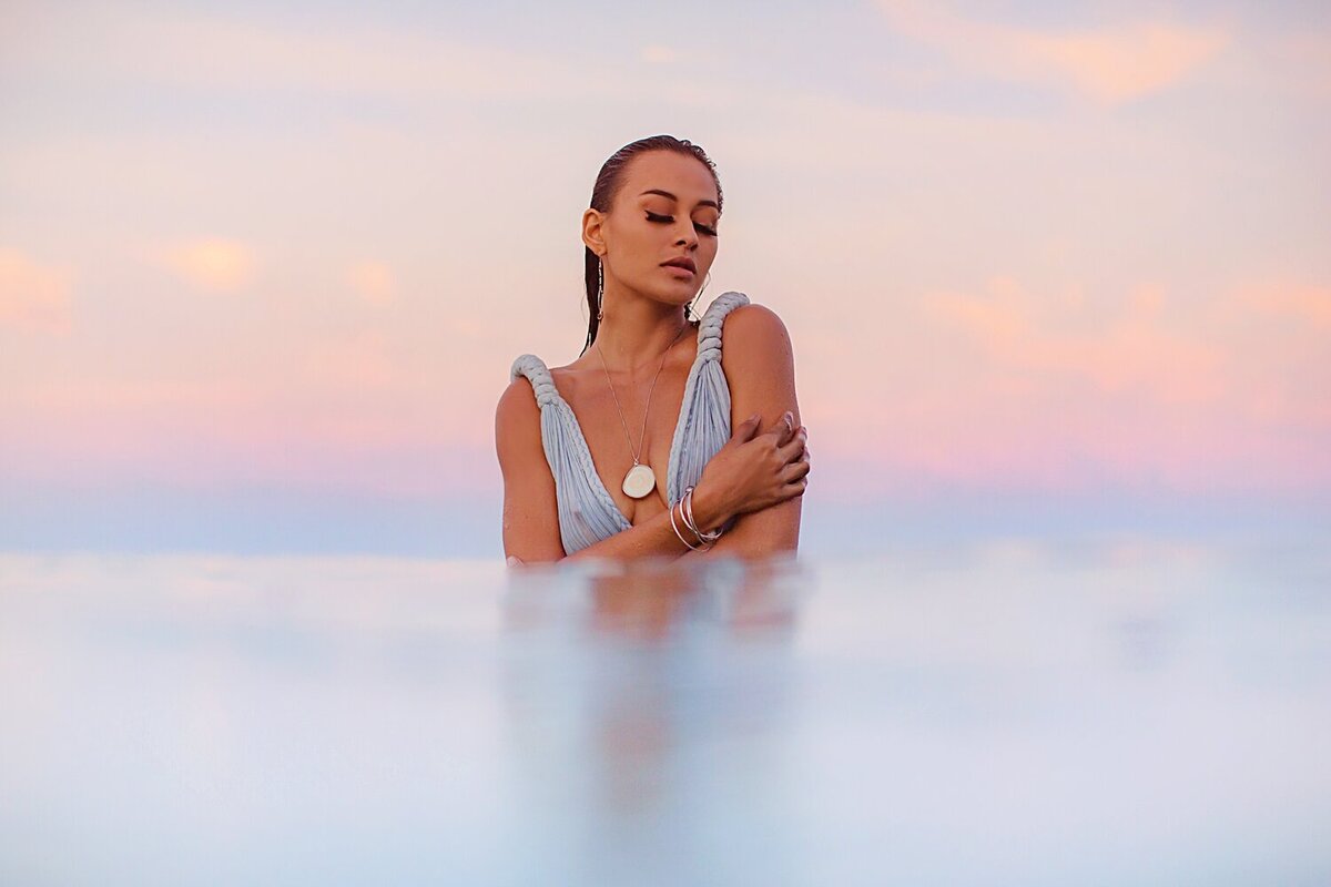 Woman in Kasia Kulenty gown closes her eyes during her sunrise portrait session