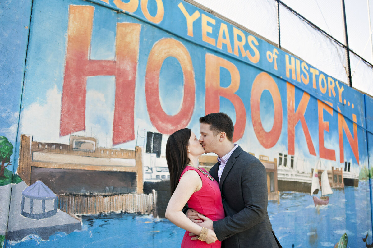 A couple kissing in front of a Hoboken mural 