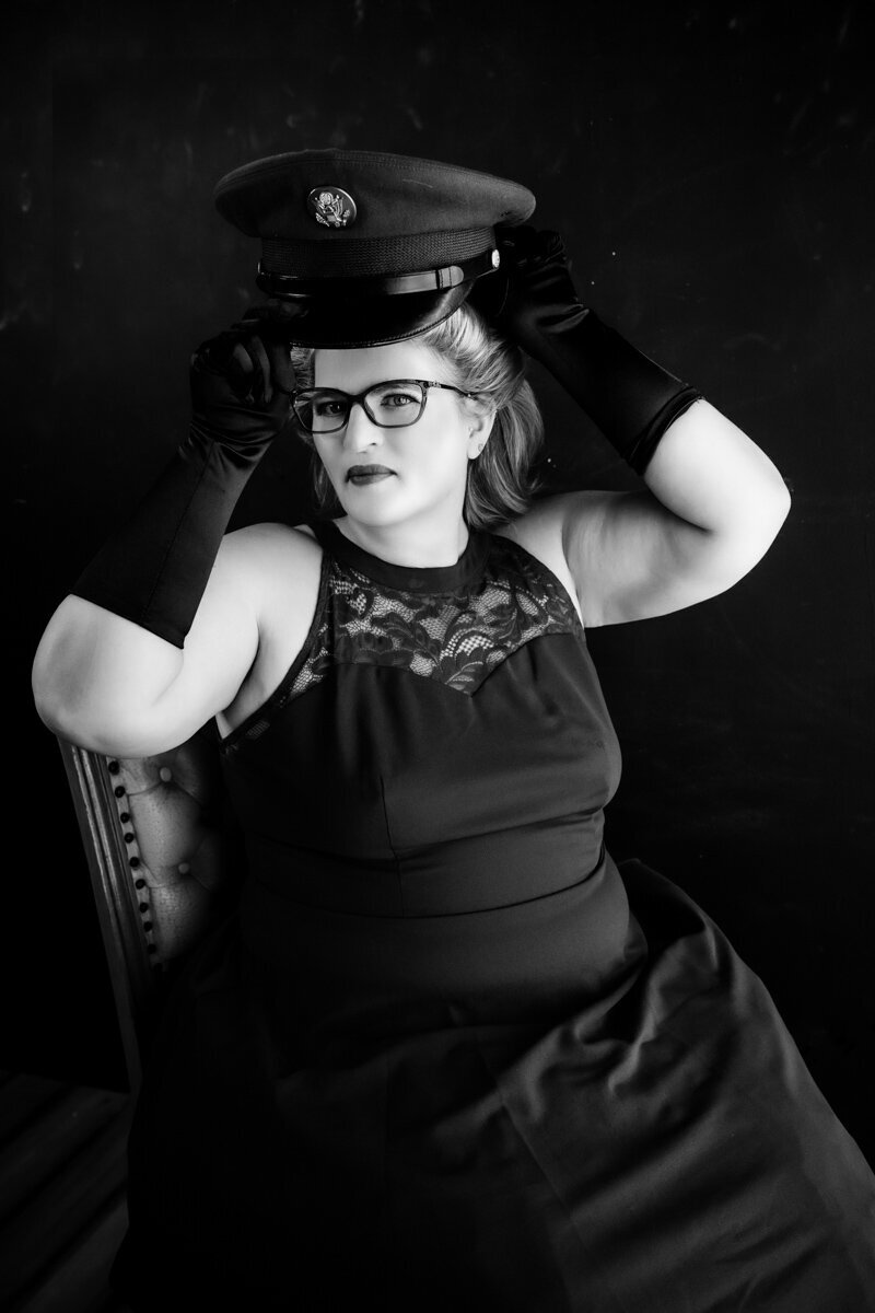 woman putting on a vintage army hat sitting in a chair photo is in black and white