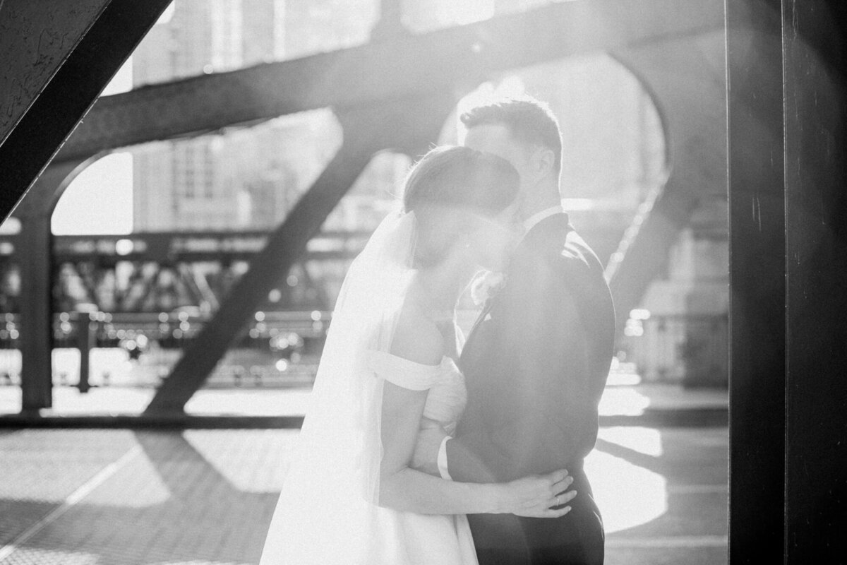 A sunlit portrait of a couple embracing on the LaSalle Street Bridge in Downtown Chicago