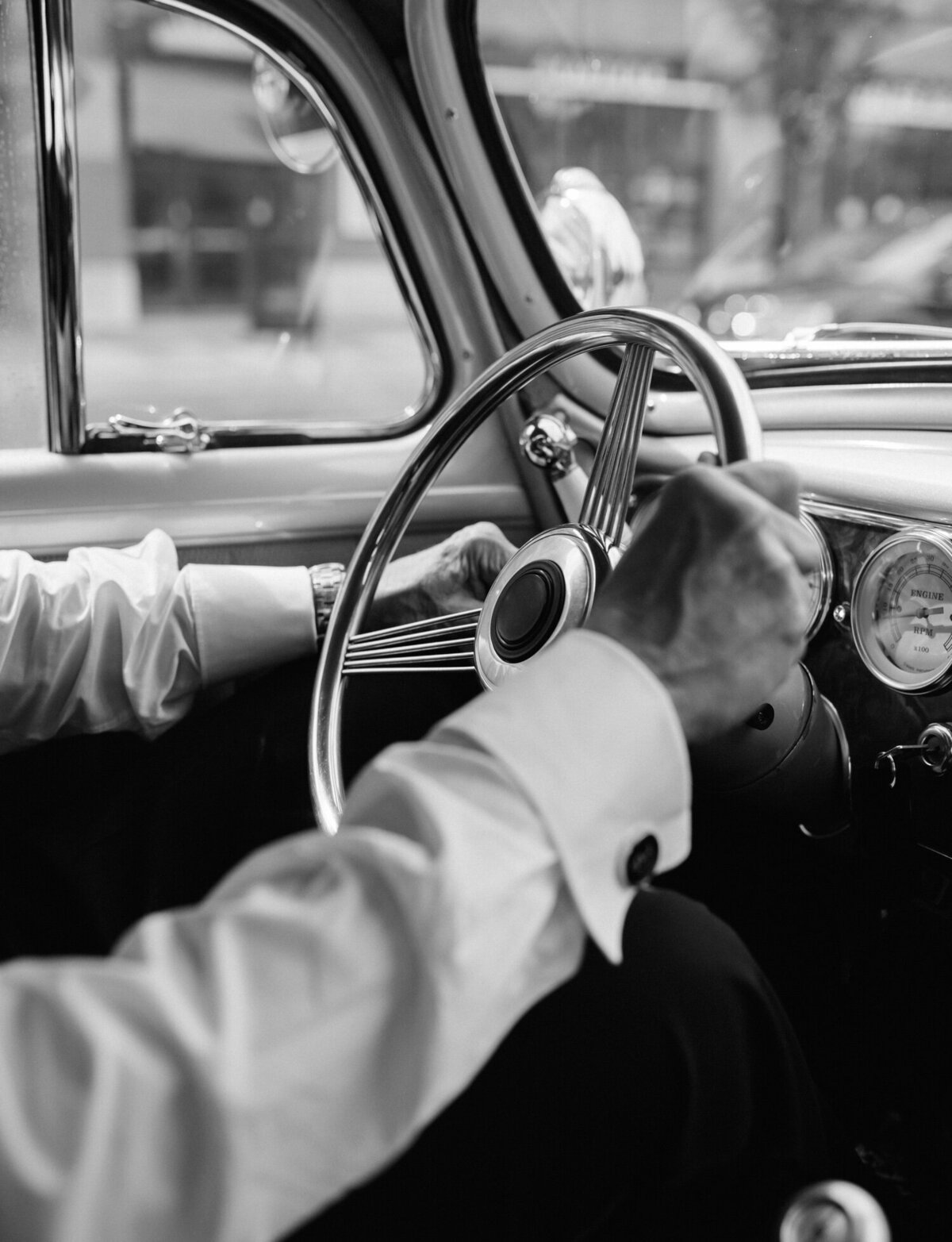 driver's hands on wheel of vintage wedding car in Detroit, Michigan